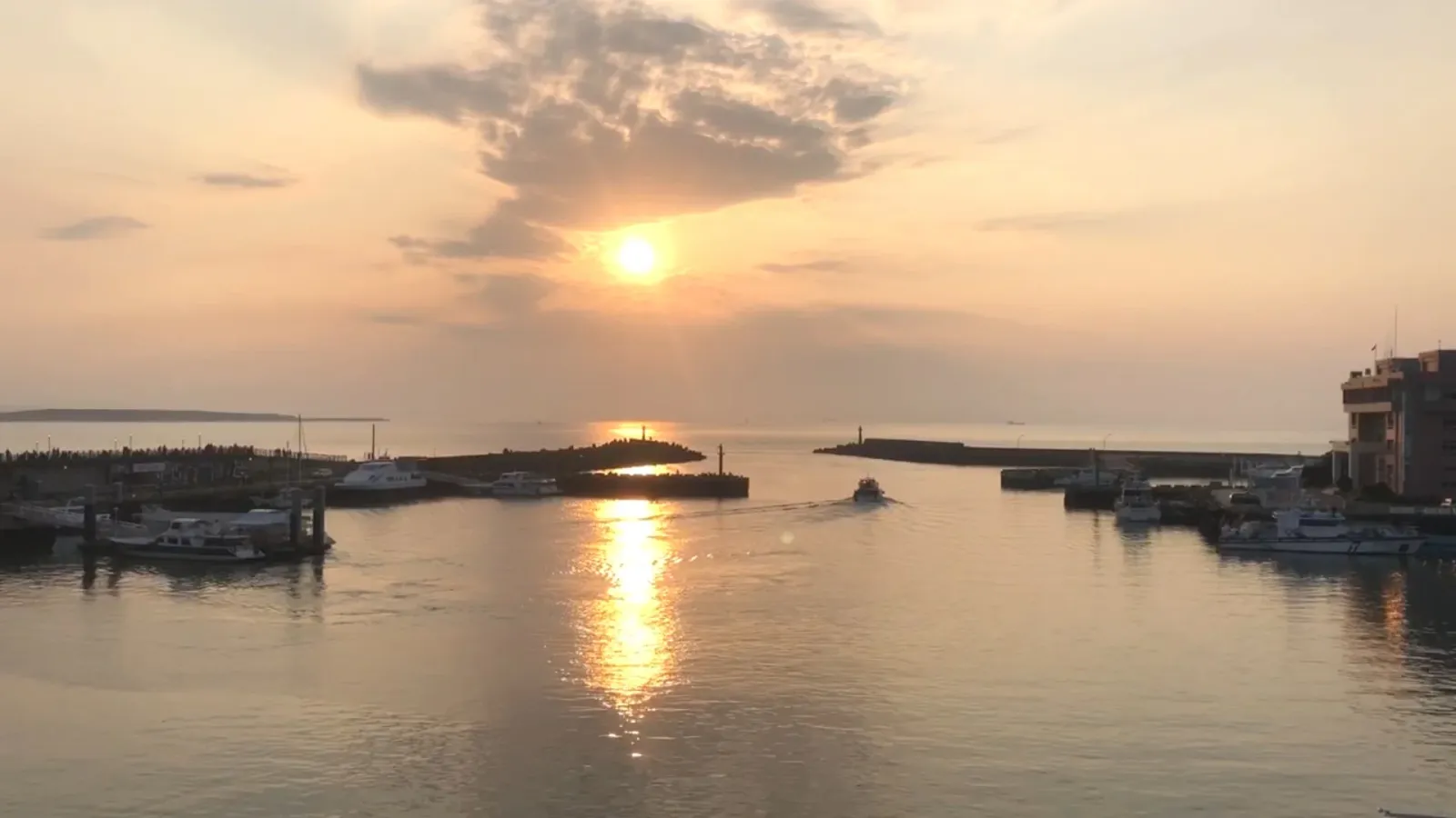 淡水漁人碼頭的夕陽，一艘船正駛出港口